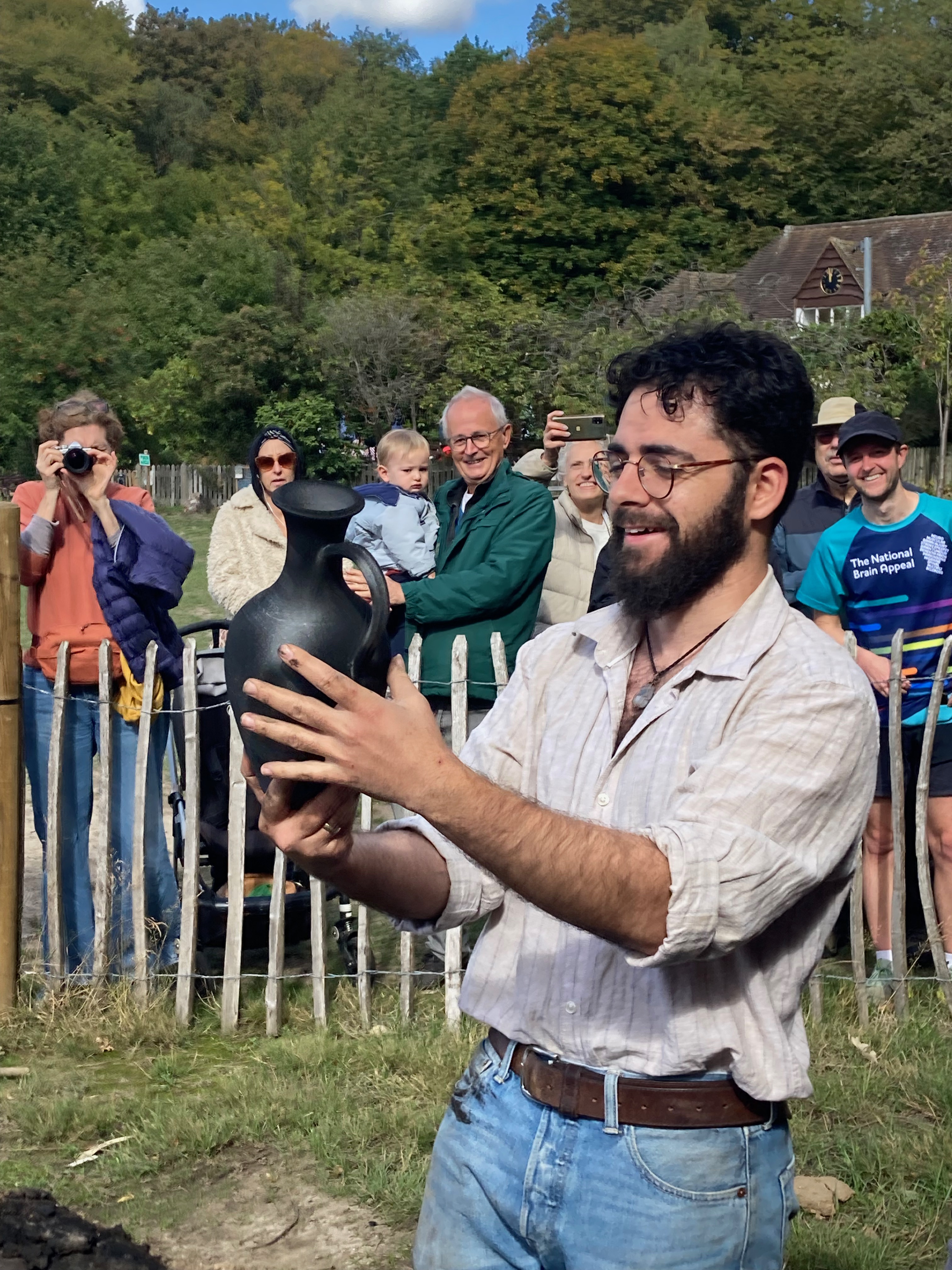 Potter Shem Morgan inspecting a piece fired in the replica kiln